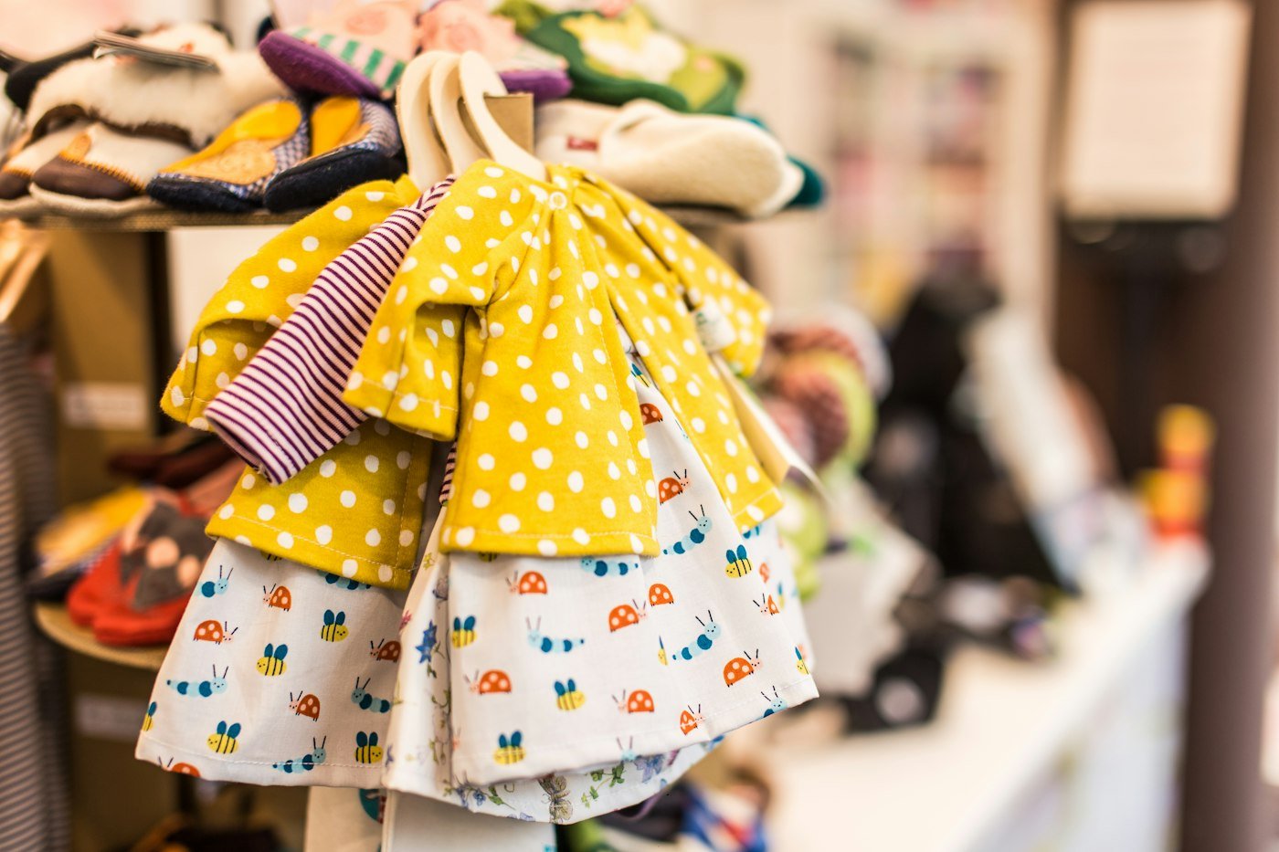 Roupas infantis coloridas em cabides, com peças leves de manga curta.